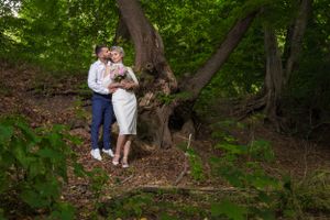 A romantic moment captured in a sunlit forest clearing.