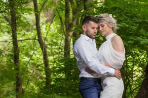 Intimate moment captured between couple surrounded by lush summer foliage.