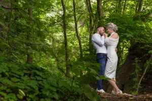 A romantic woodland photoshoot with a couple among green summer foliage.