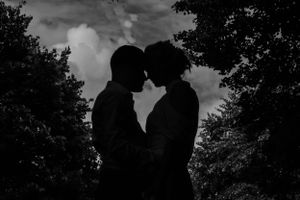 Silhouetted figures create a romantic scene against a dramatic sky.