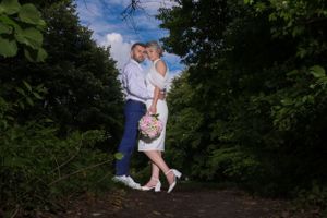 A couple poses for wedding photos in a sunlit garden setting.