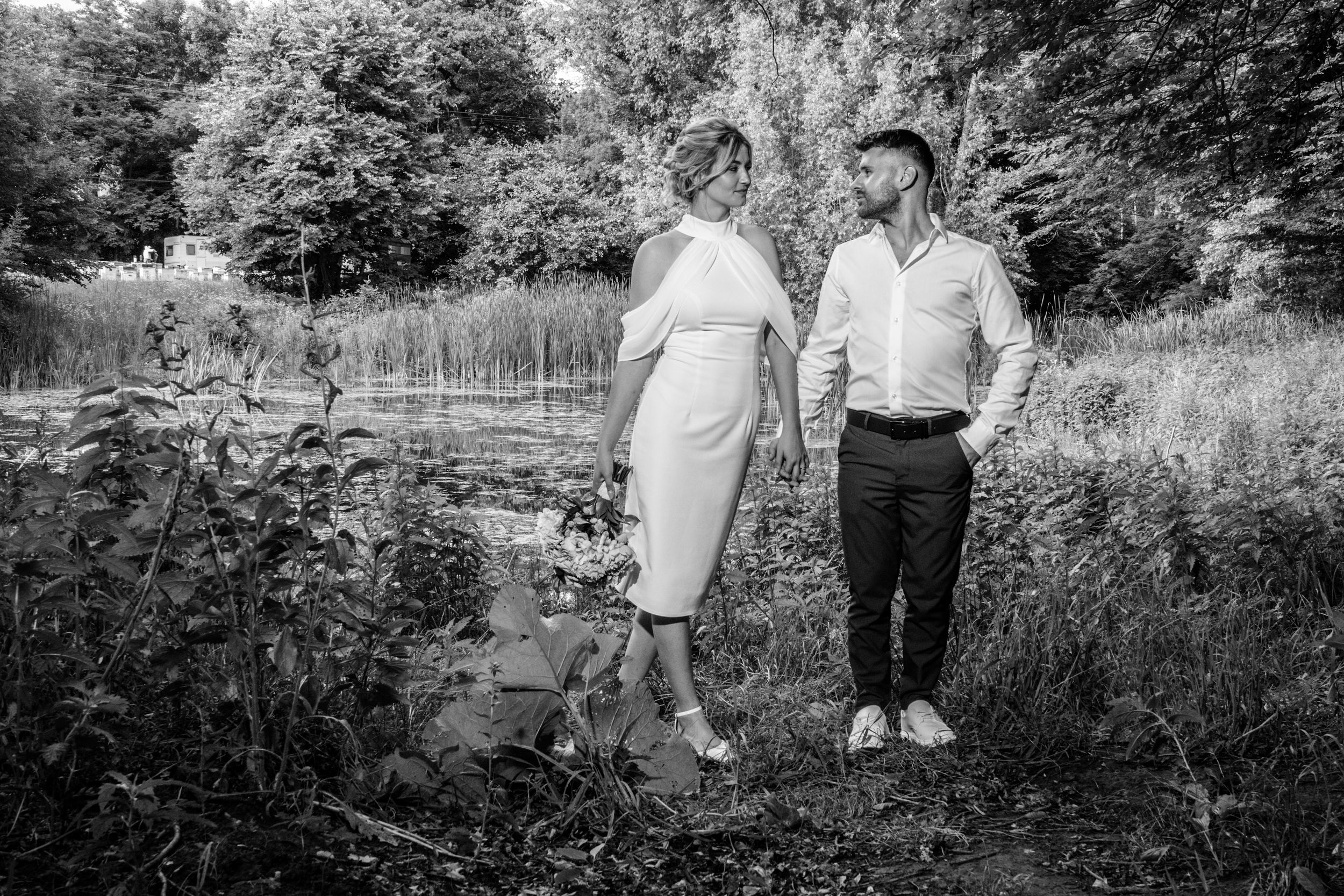 A black and white photo of a couple walking through a scenic garden landscape.