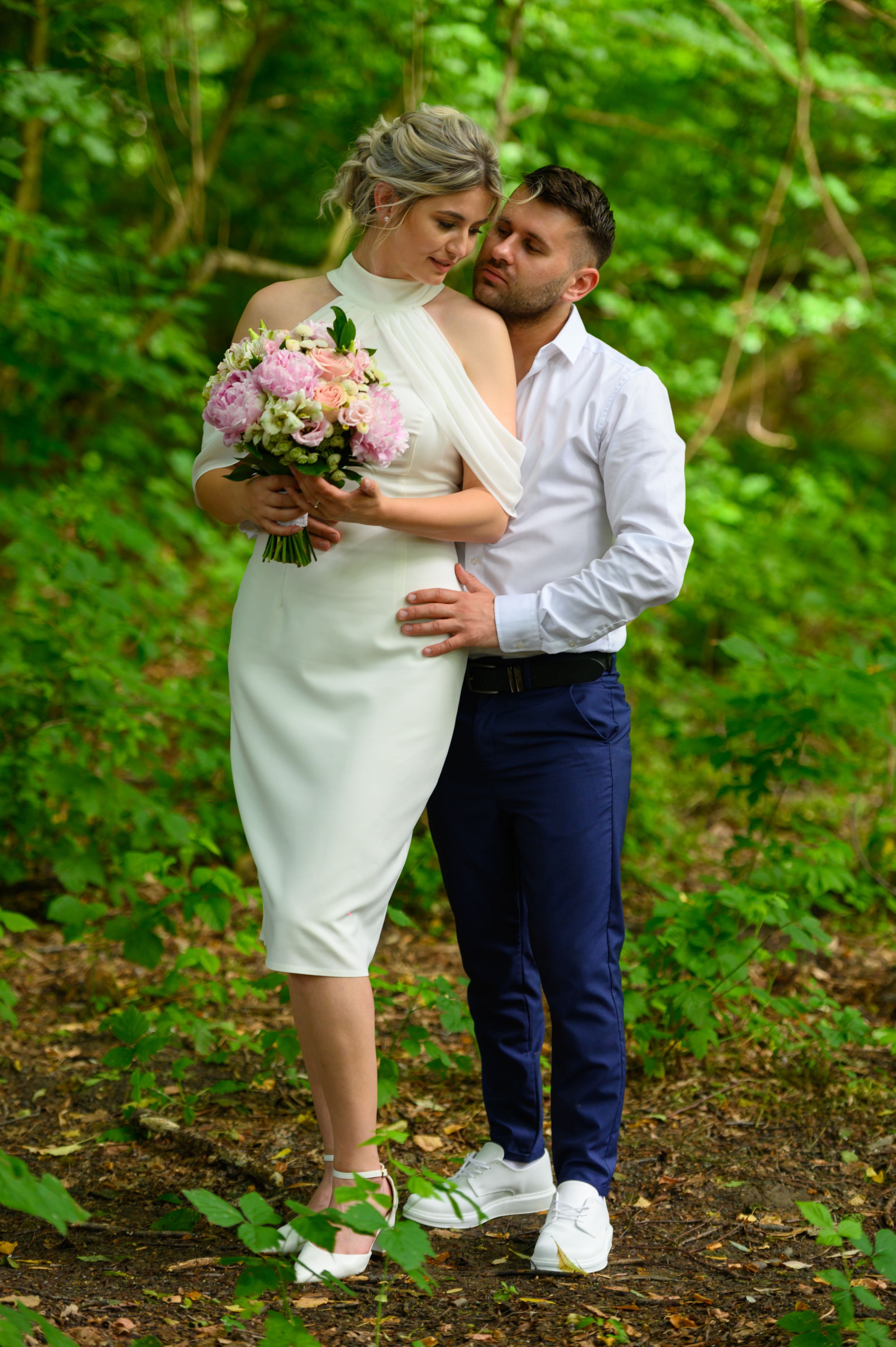 Intimate couple's portrait session in a wooded area with natural lighting and white attire.