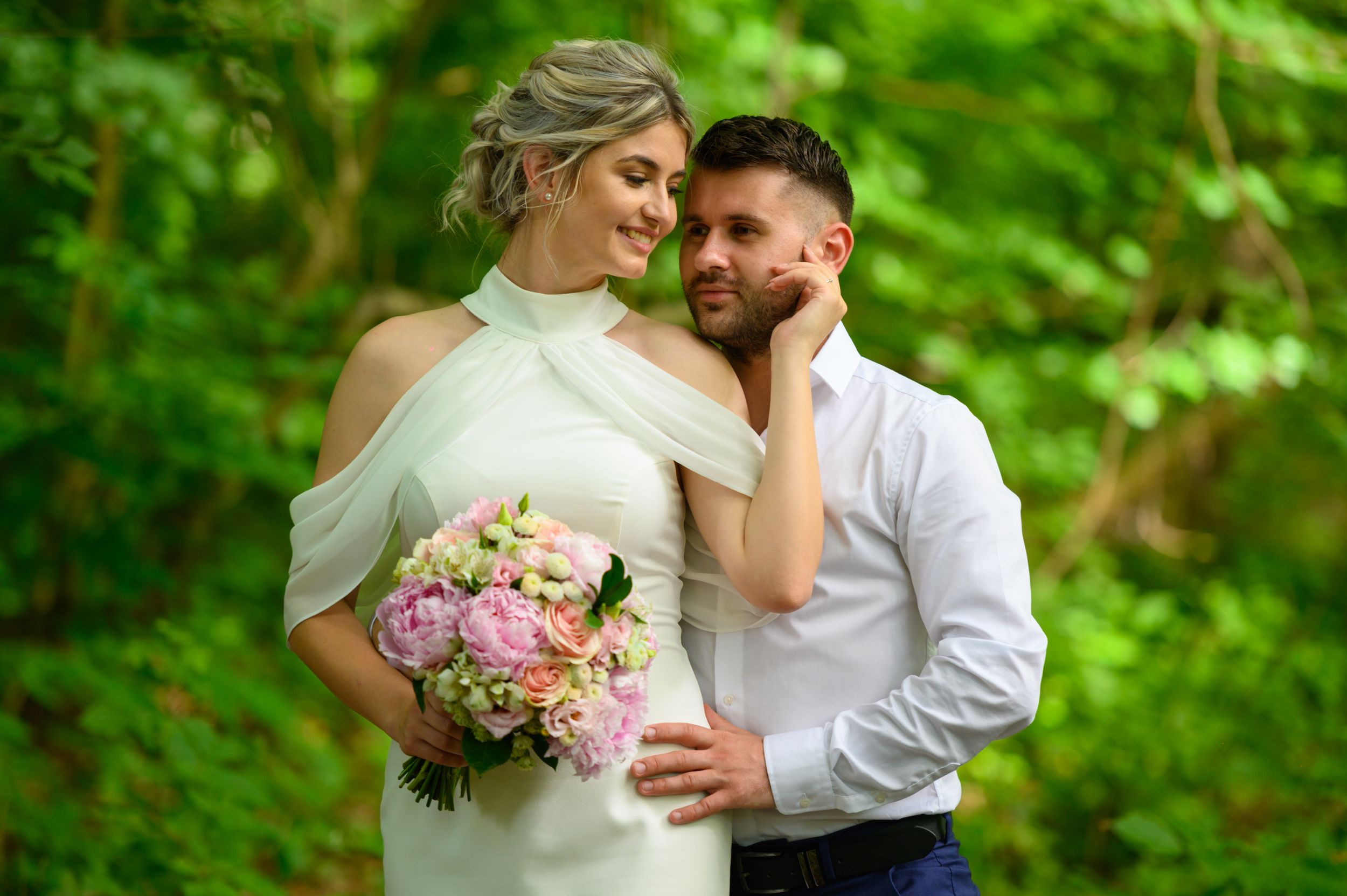 Tender moment photographed against vibrant green foliage with spring flowers.