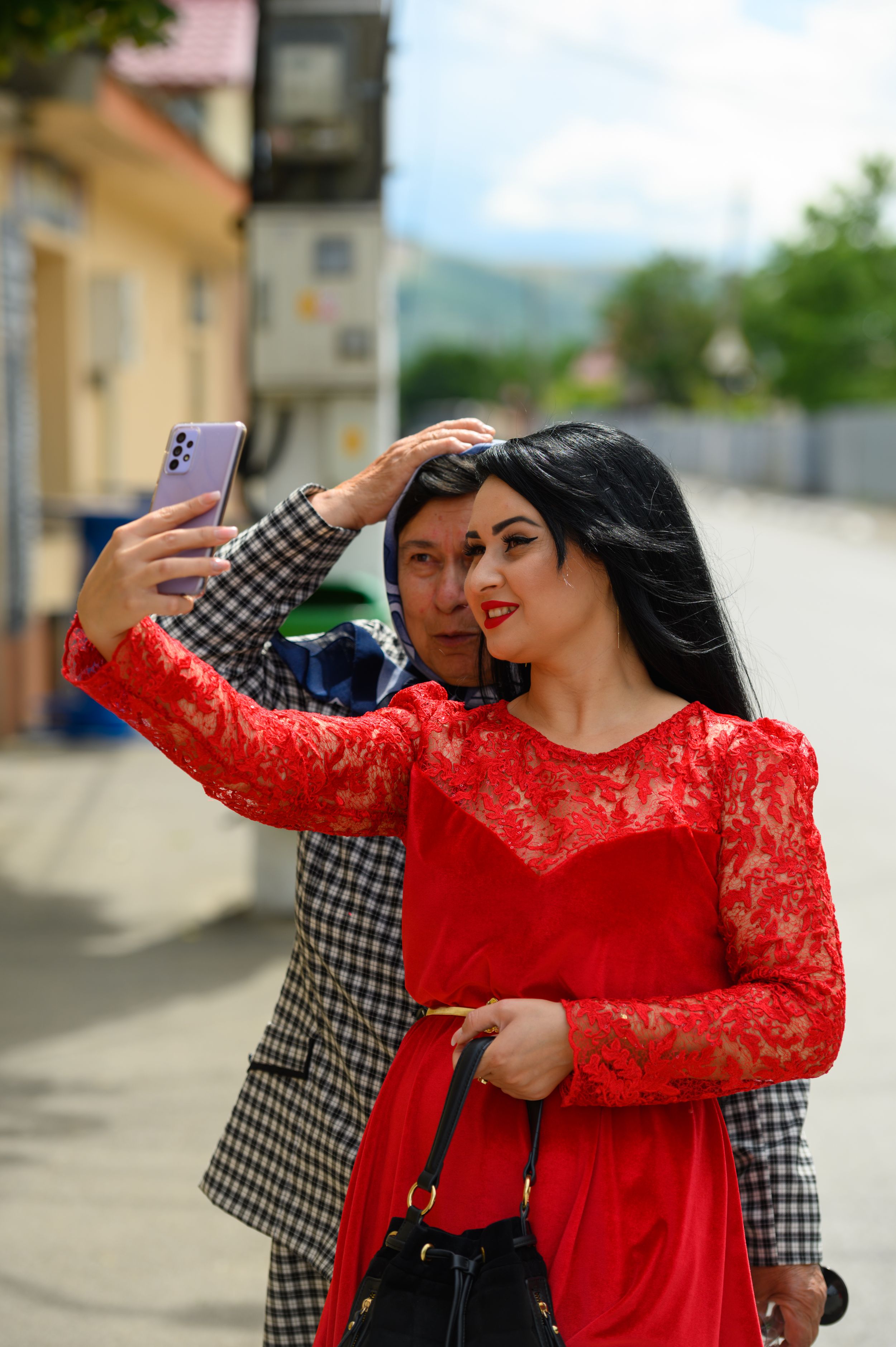 Two people in contrasting red lace and checkered outfits posing on a city street.