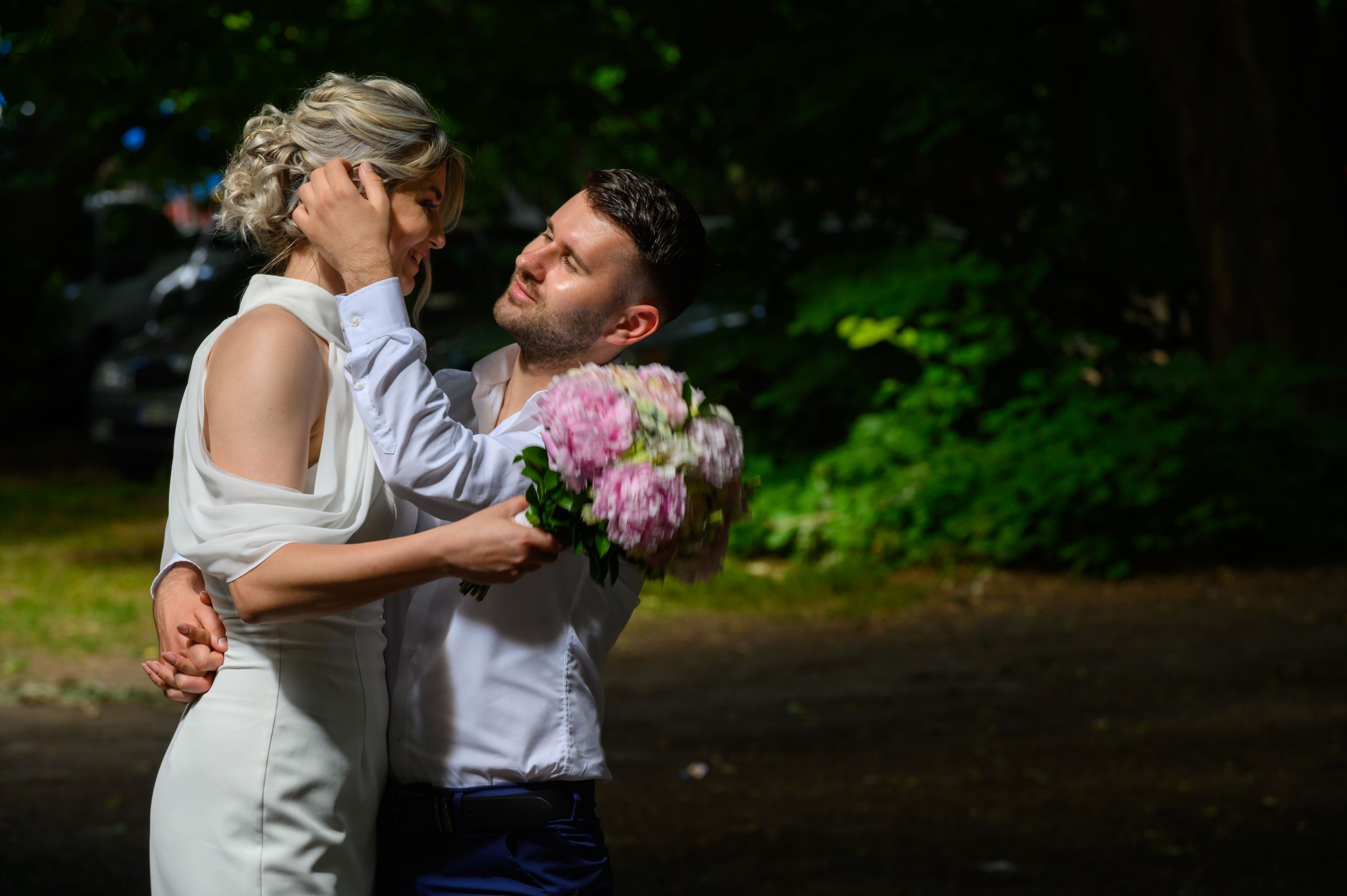 Artistic wedding photography with dramatic lighting in a dark forest setting.