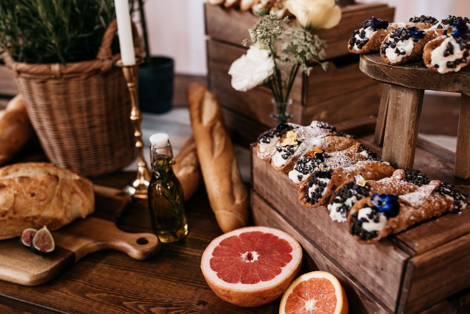 Artisanal pastries and citrus fruits displayed on wooden crates with fresh herbs and greenery.