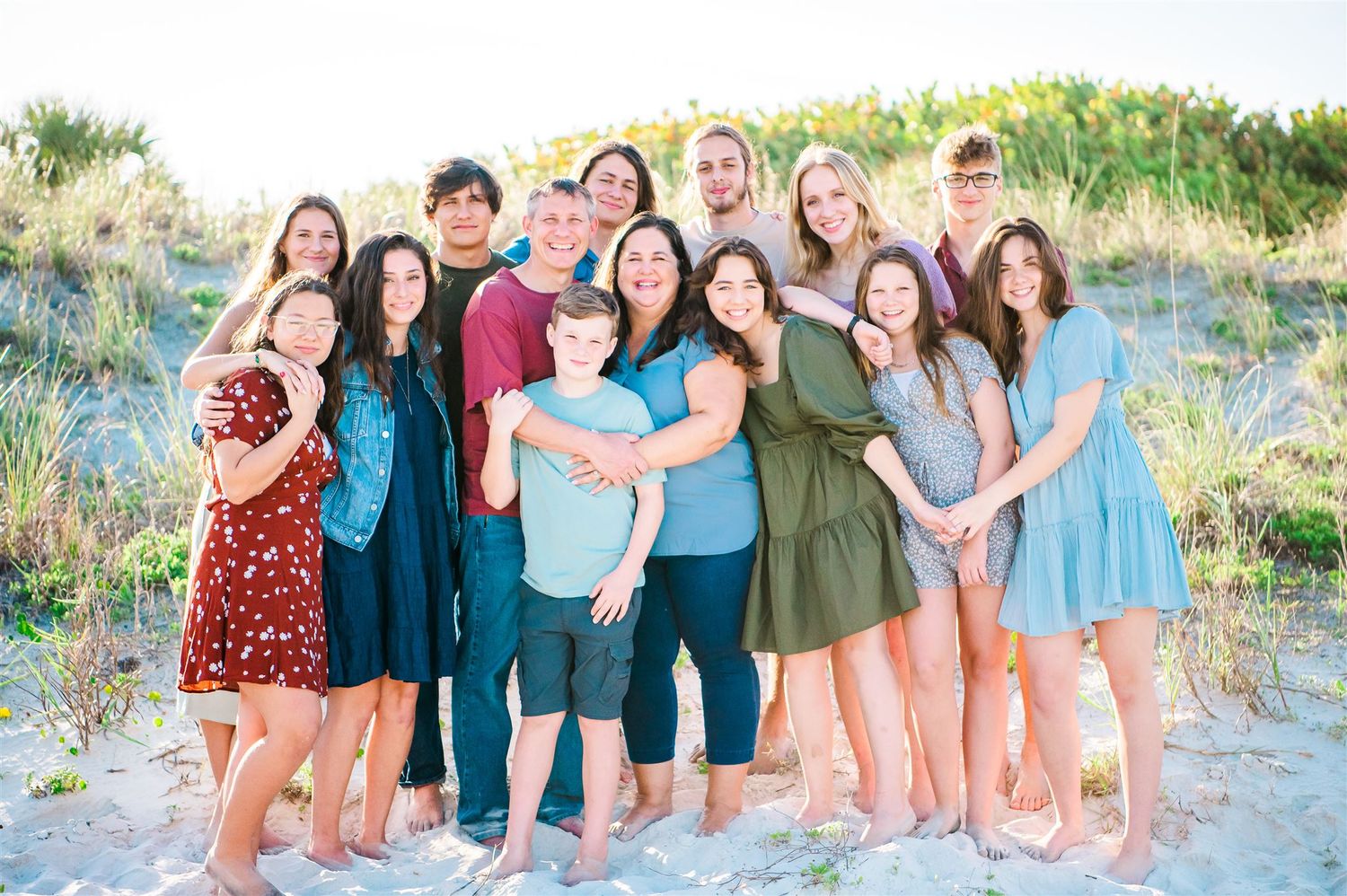 Group of friends gather together on sandy beach for casual outdoor photo.