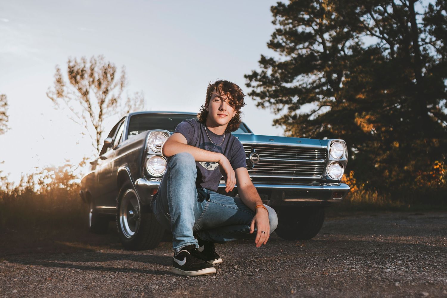 Moody sunset portraits with vintage cars creating silhouettes against orange sky. Middle TN senior photographer