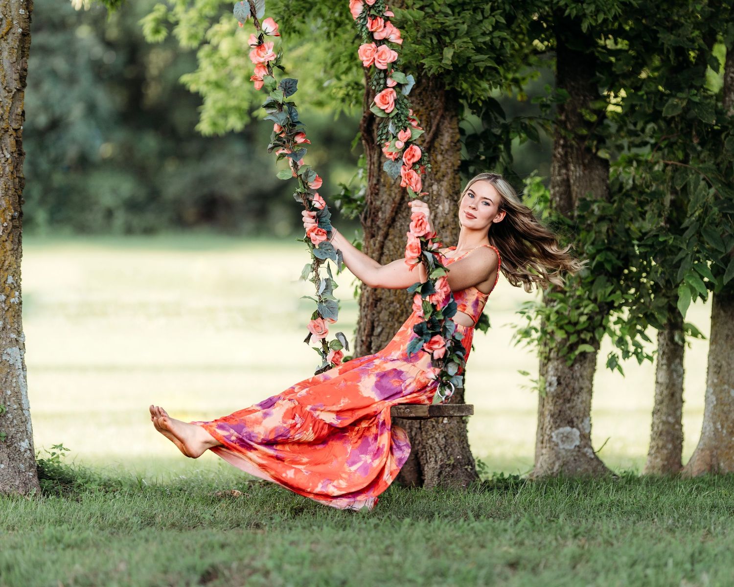 Red dress flowing in  breeze among trees during outdoor photo session. Middle TN senior photographer