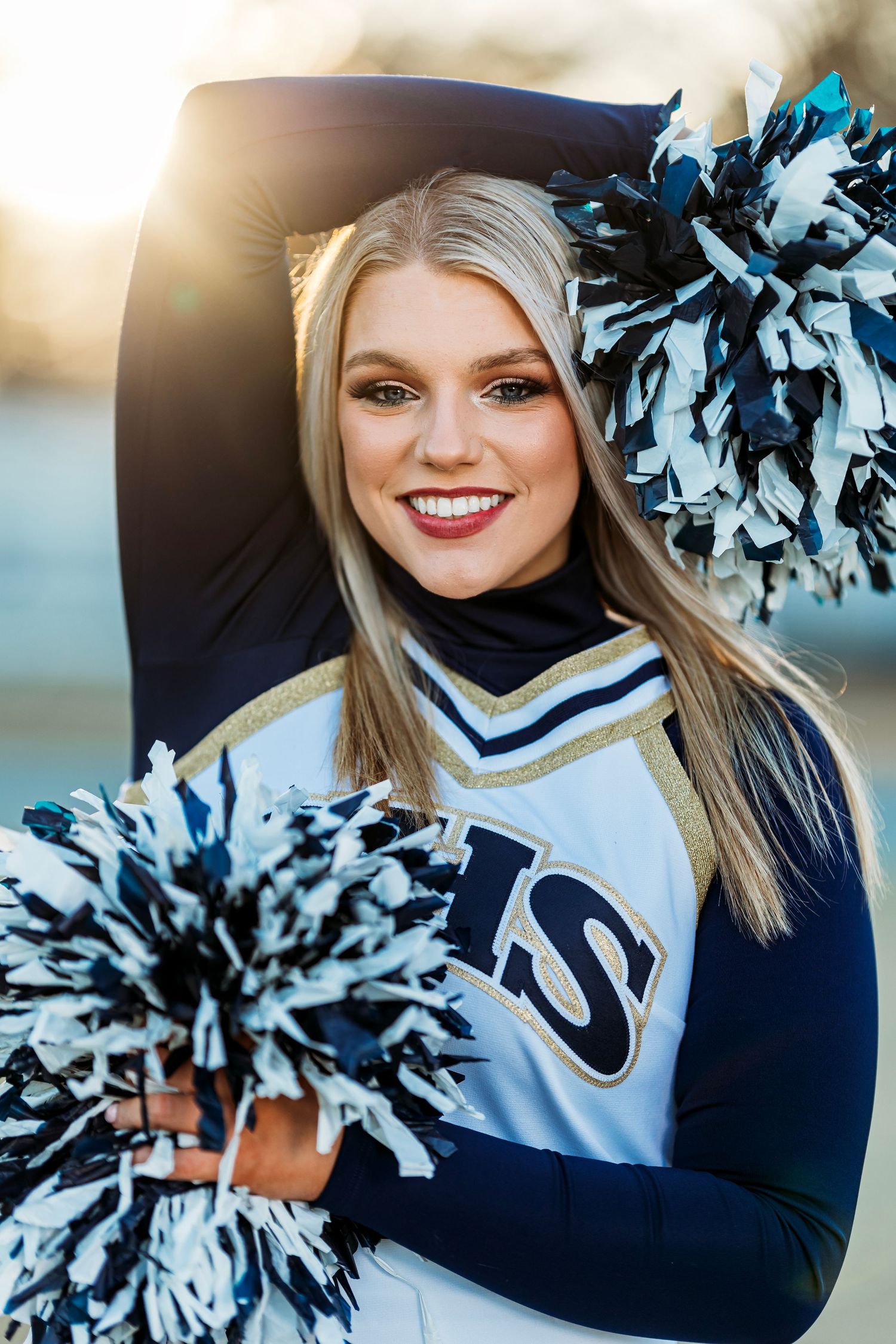 Cheerleader in blue and white uniform with pom poms performing outdoors. Middle TN senior photographer