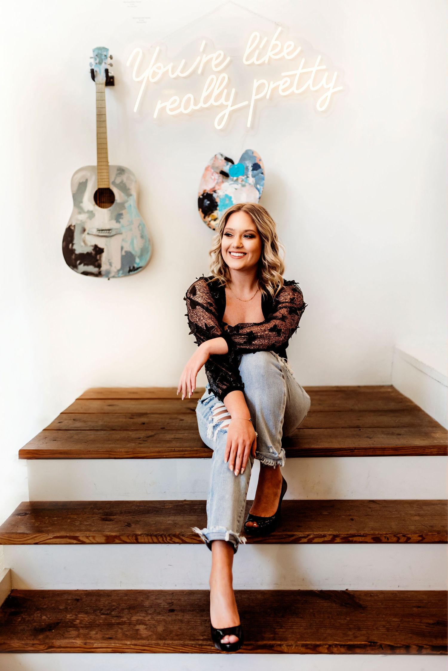 Casual portrait session on wooden bench with neon sign and guitar decor. Middle TN senior photographer