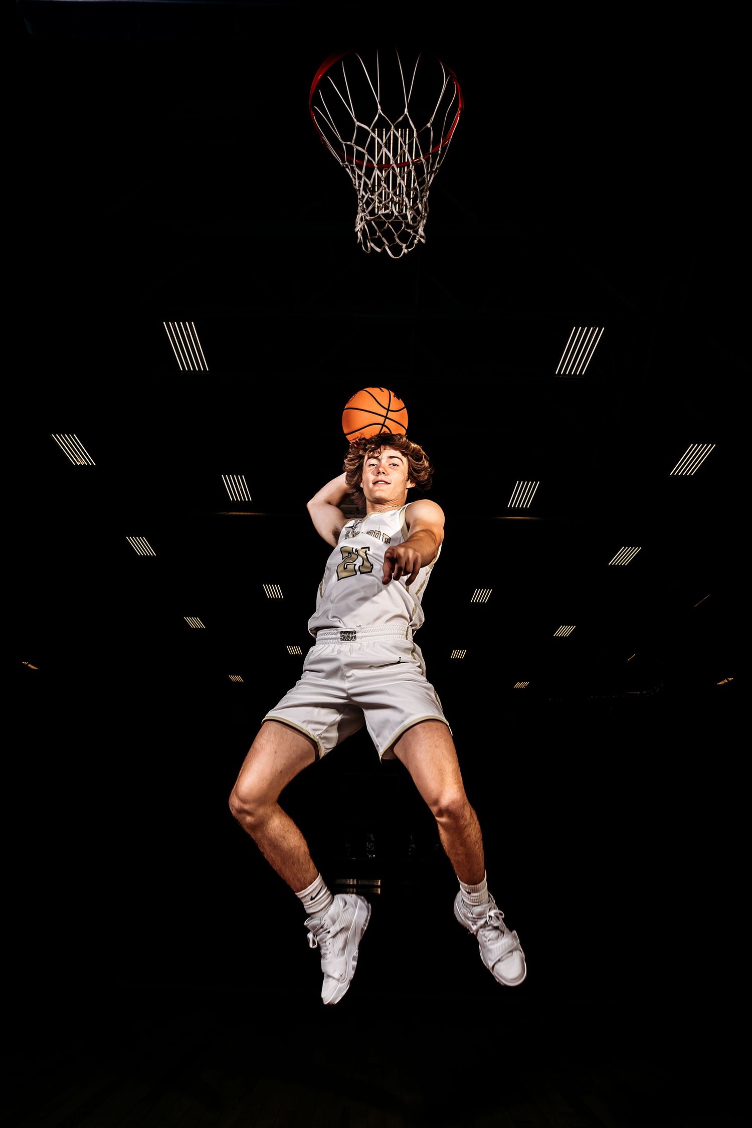 Basketball player in white jersey performing slam dunk sequence against black background. Middle TN senior photographer
