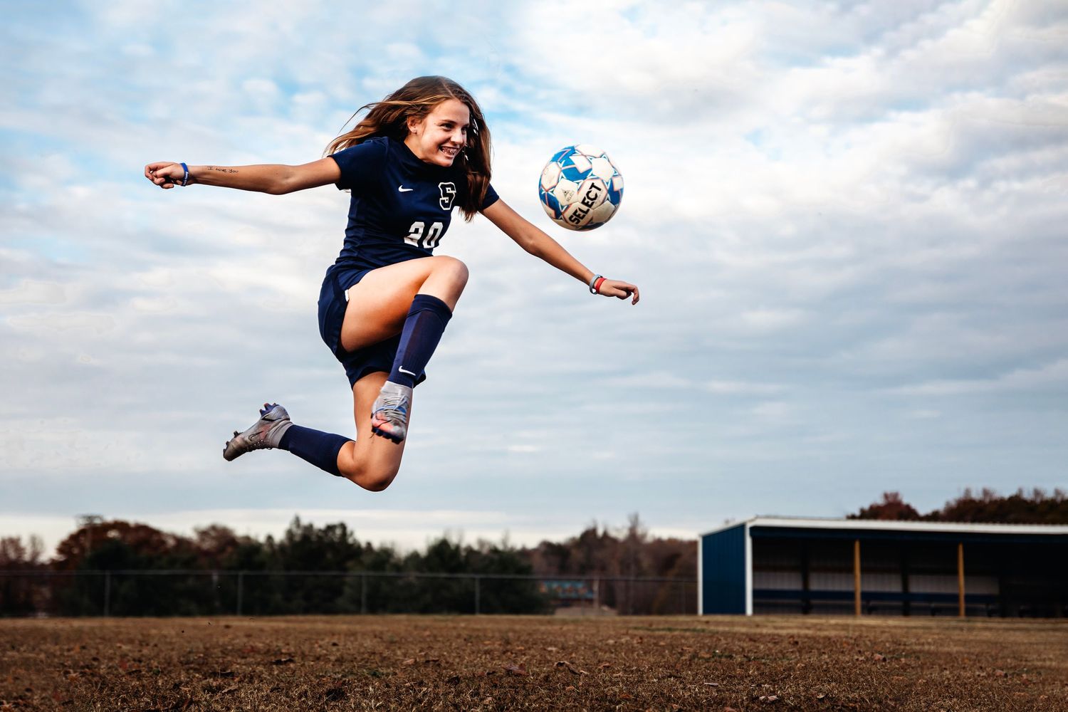 Soccer player performing acrobatic kick against cloudy sky on open field. Middle TN senior photographer
