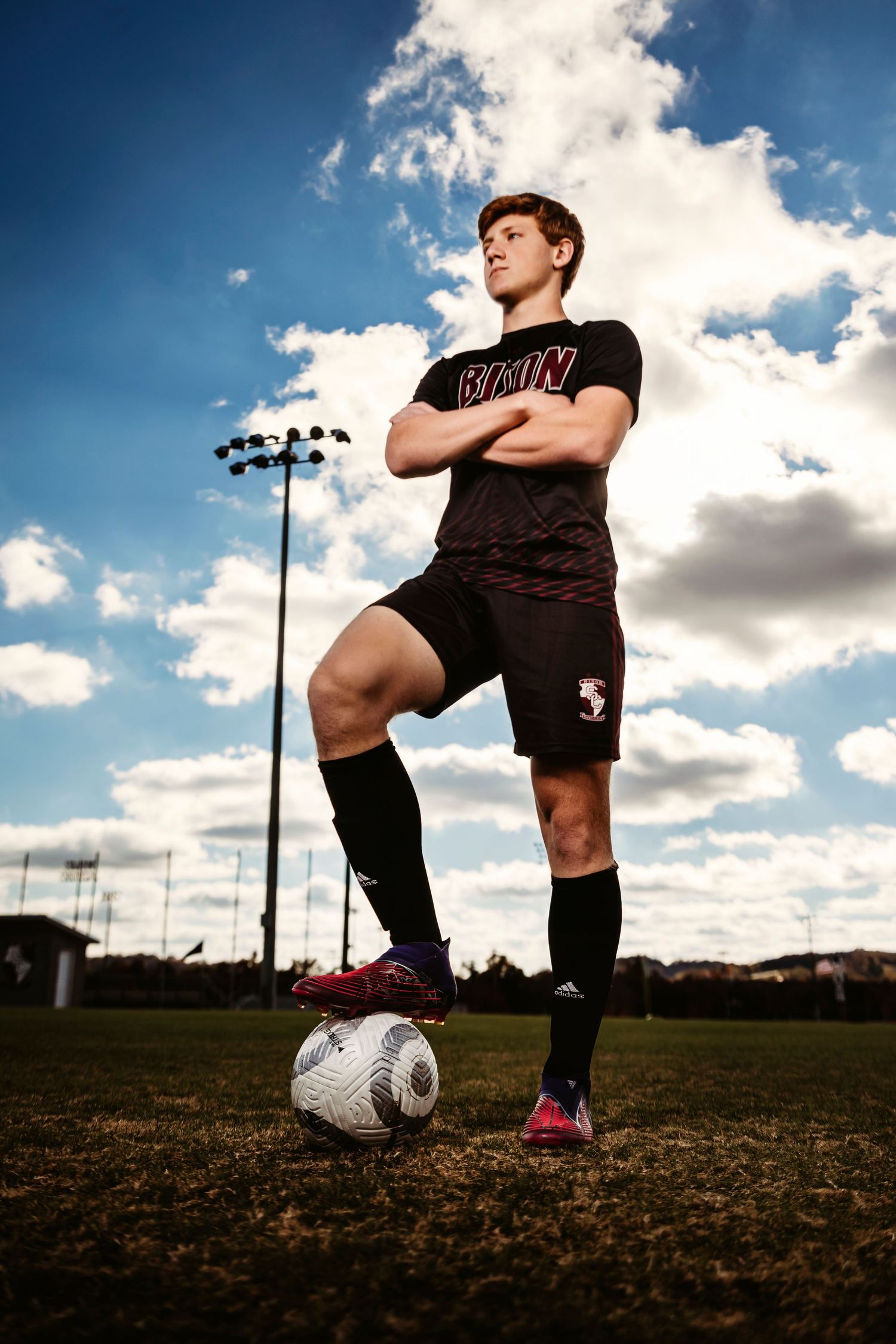 Soccer player posing with ball on field under dramatic cloudy sky.  Middle TN senior photographer