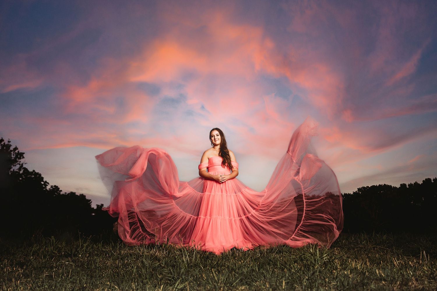 Flowing pink dress against dramatic sunset sky in an open field.Middle TN senior photographer