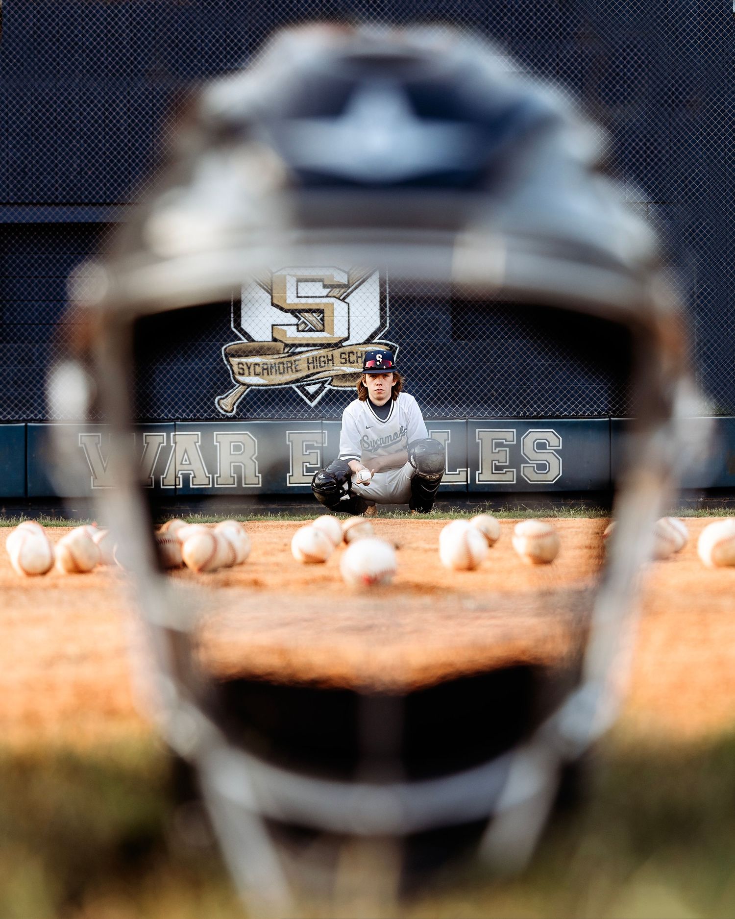 Close-up of baseball equipment through chain link fence with blurred background. Middle TN senior photographer