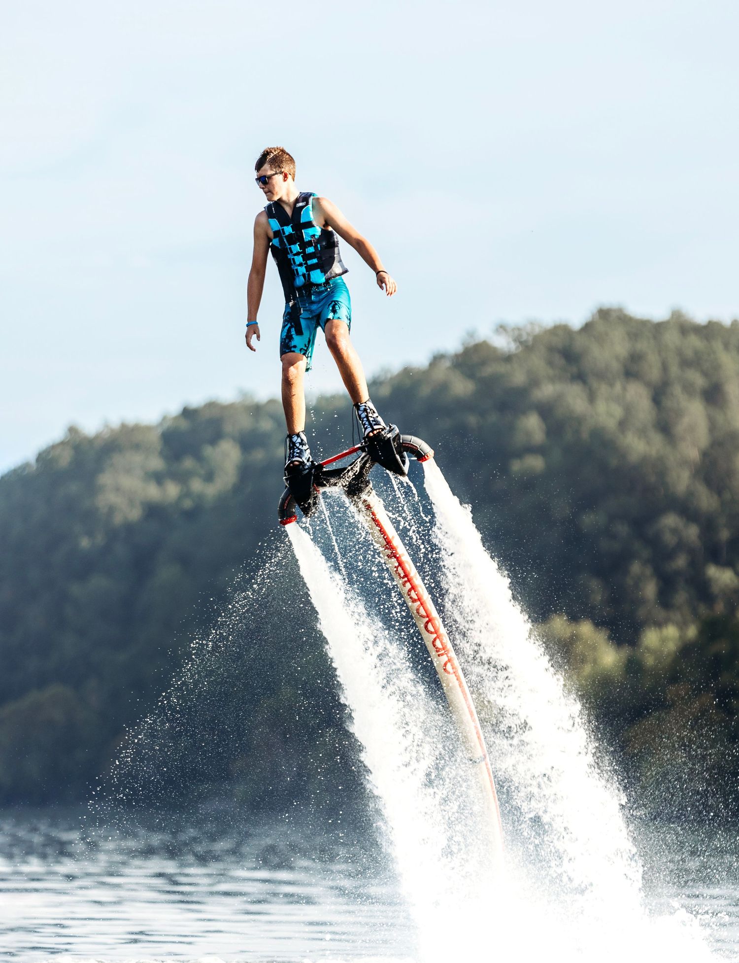 senior guy in blue swimwear performing impressive flyboard stunts over a lake. Middle TN senior photographer