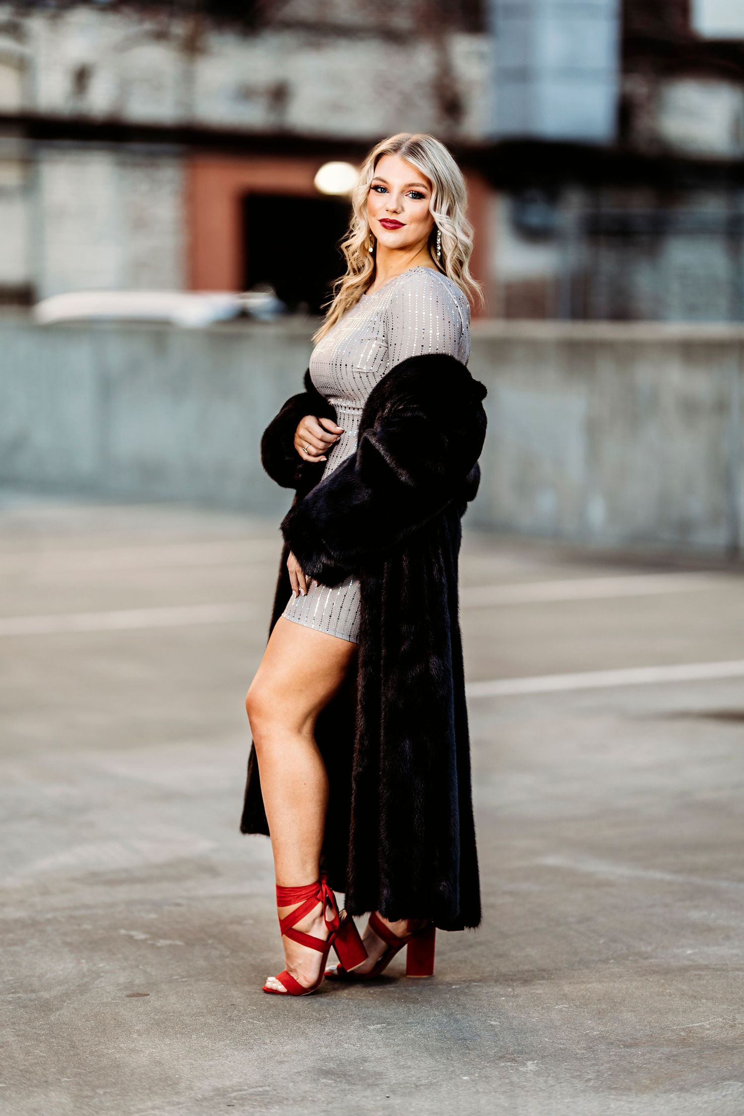 Fashion portrait of woman in black coat and red heels on Nashville parking lot concrete background. Middle TN senior photographer