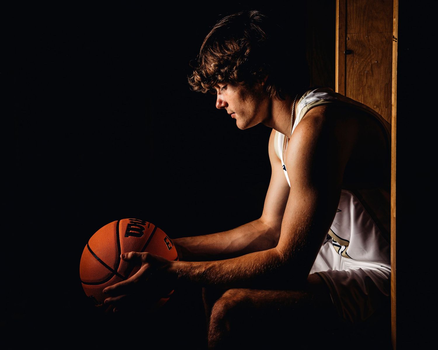 Dramatic side-lit photo of basketball player practicing dribbling moves. Middle TN senior photographer