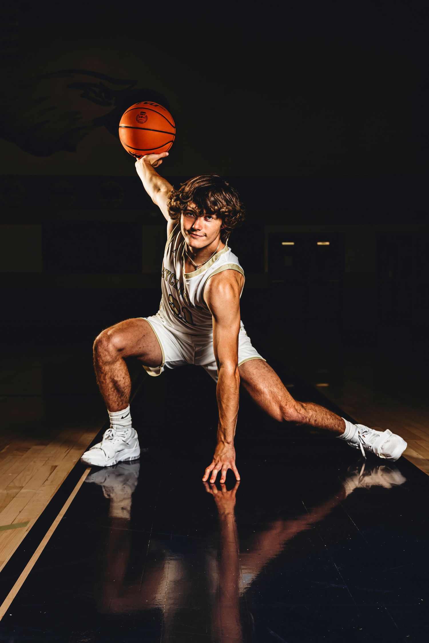 Athletic figure performs low ground moves with basketball in dramatic lighting. Middle TN senior photographer