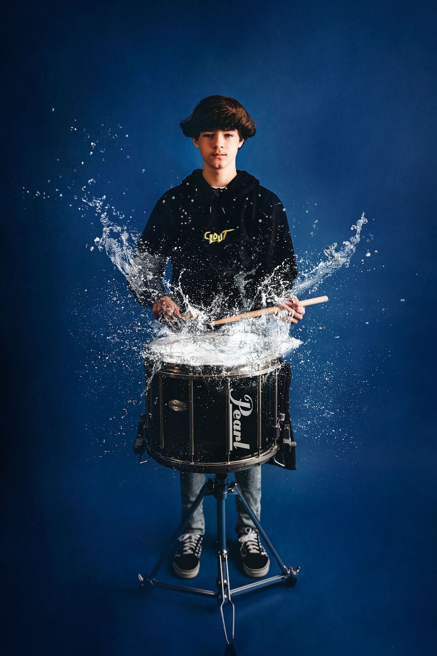 Drummer creating dramatic water splash effect during performance against blue backdrop. Middle TN senior photographer