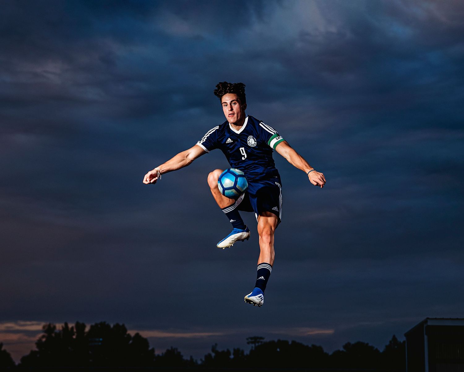 Soccer player performs acrobatic kick against dramatic sunset sky. Middle TN senior photographer