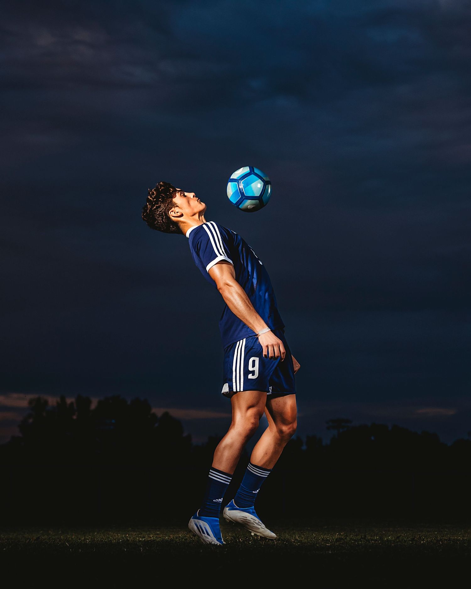 Soccer player executing bicycle kick move against dark evening sky. Middle TN senior photographer