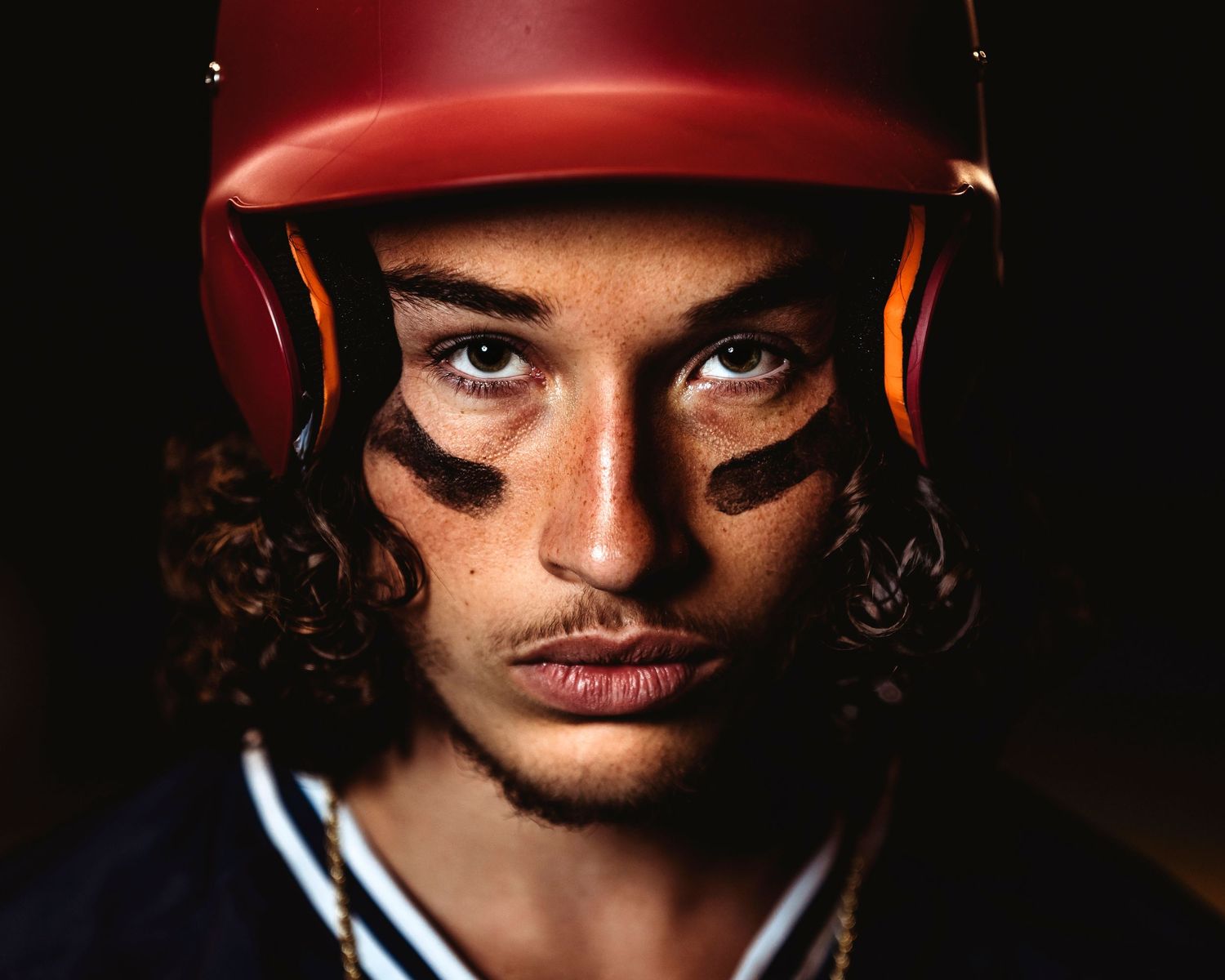 Dramatic close-up portrait with orange lighting and dark shadows. Middle TN senior photographer