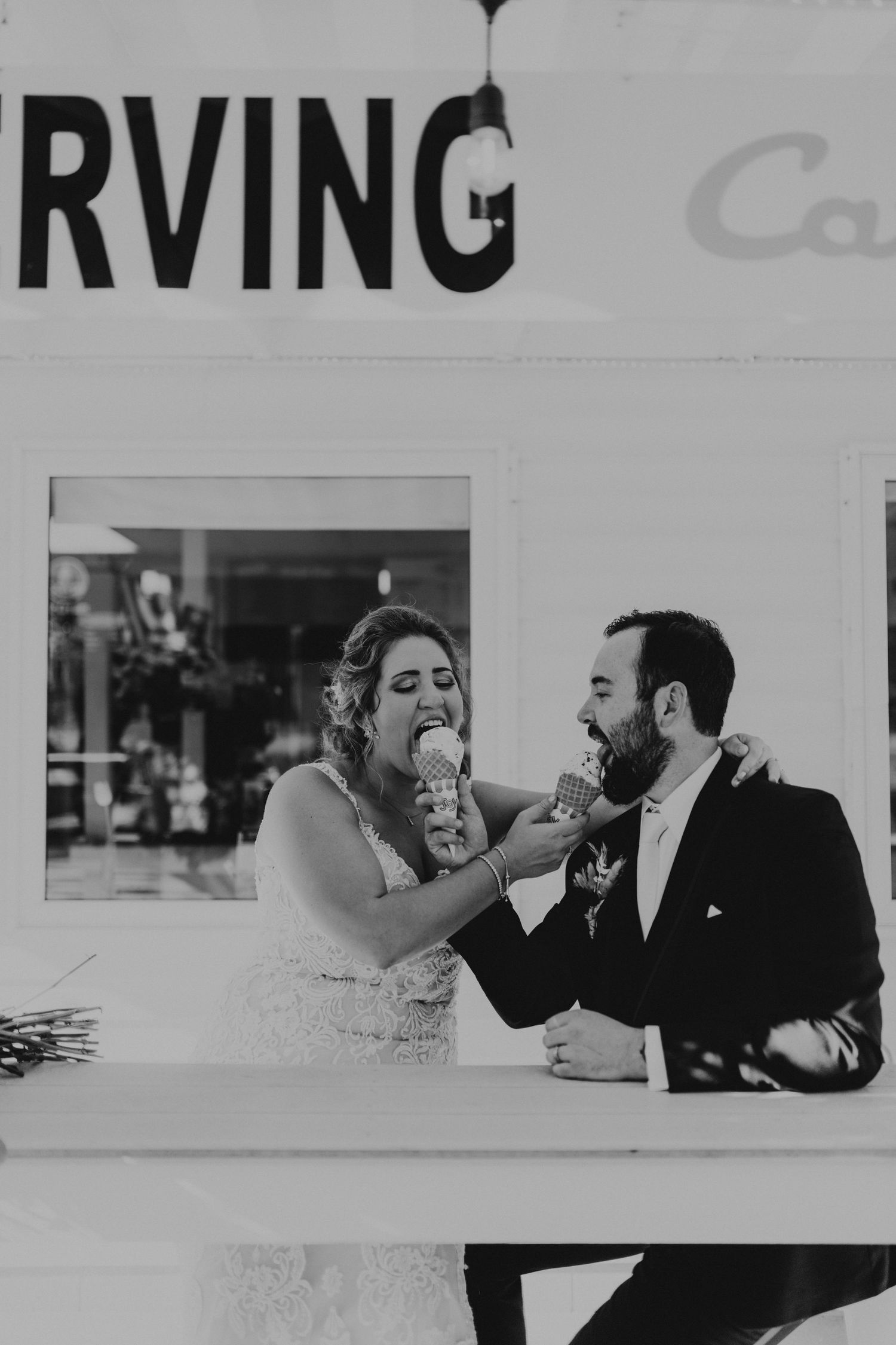 Black and white photo of couple sharing ice cream at casual dining spot.
