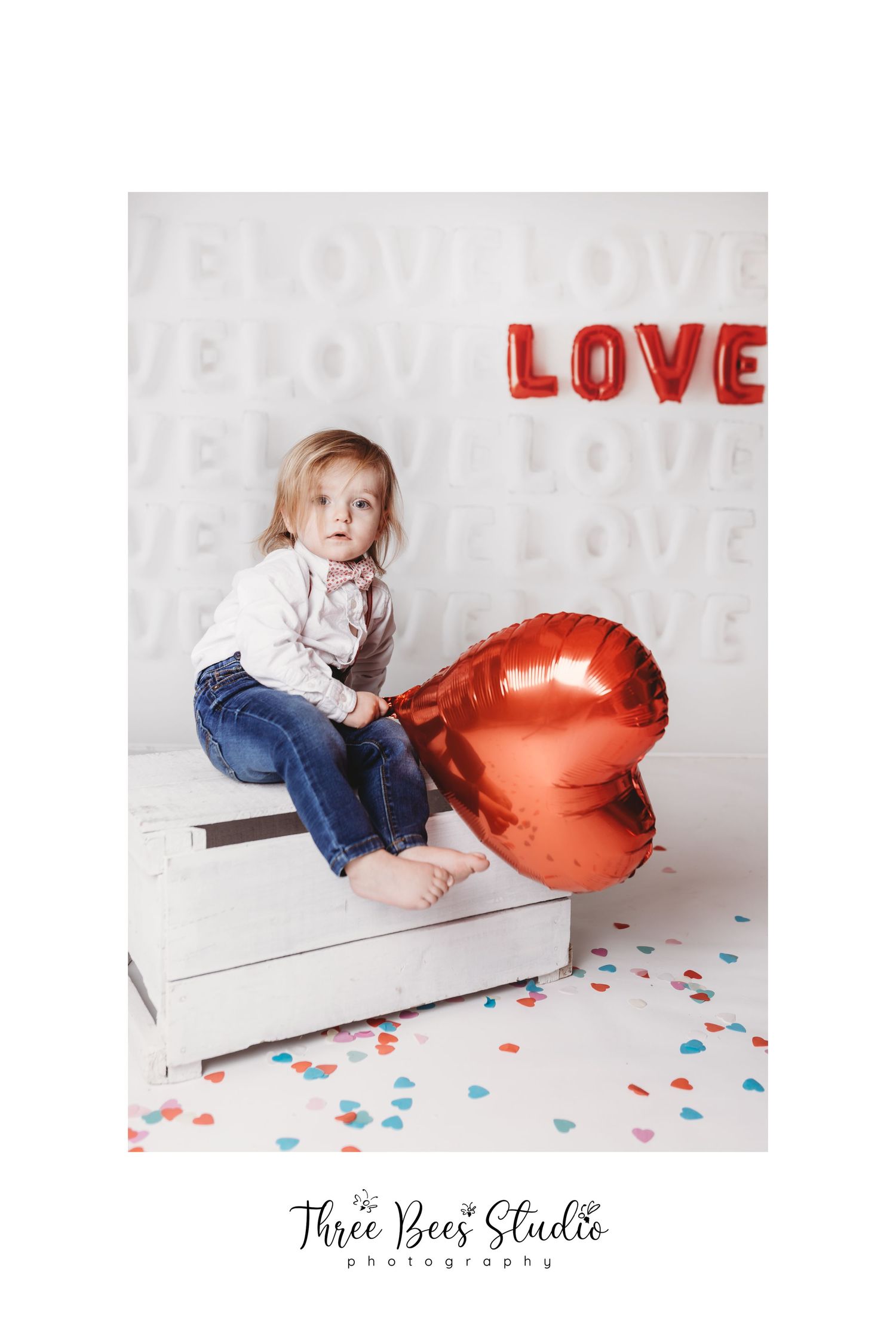 Valentine themed portrait with child and red heart balloon against white background.