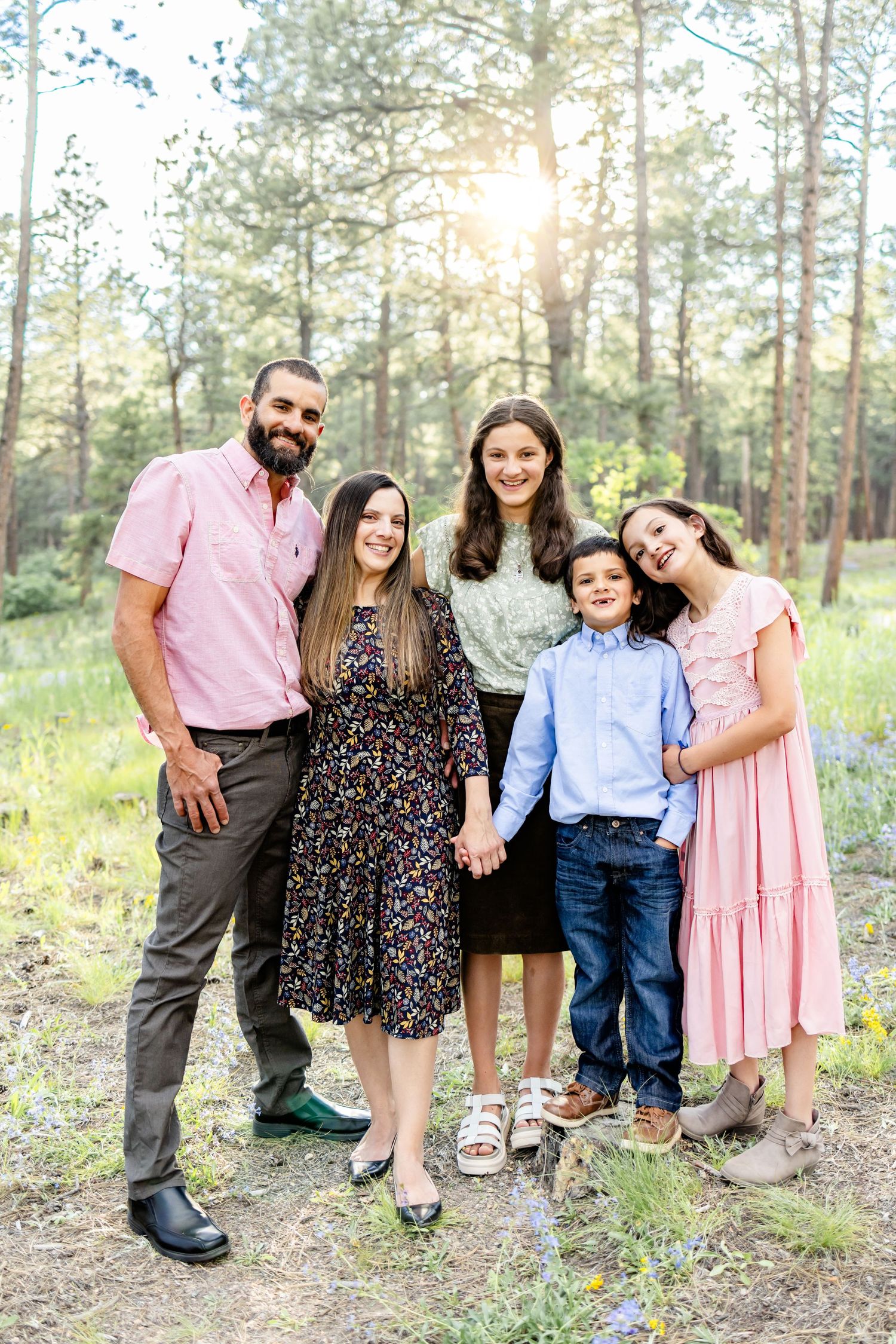 Parents and their three children stand smiling in the wildflowers during their family session in Colorado Springs.