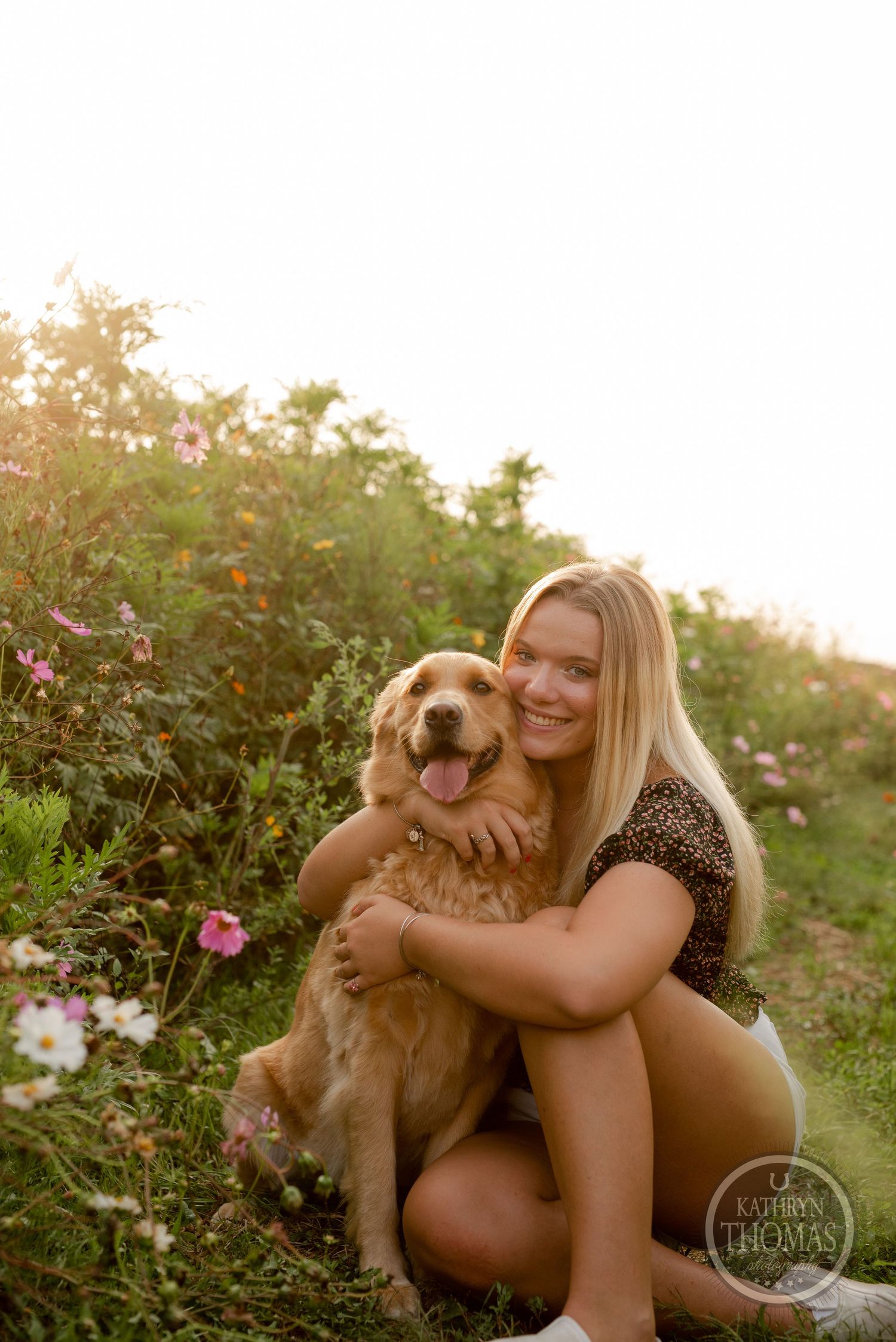 Happy golden retriever and companion sharing a sweet moment among blooming summer flowers.