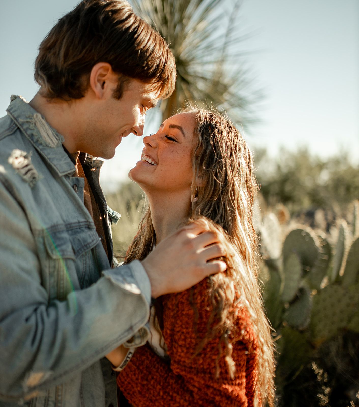 An intimate moment captured between a couple in a desert landscape with yucca plants.