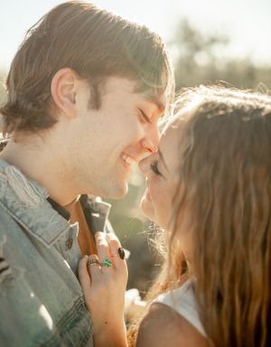An intimate close-up moment between a couple sharing a smile in warm sunlight.