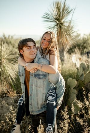 A playful piggyback ride moment captured in a desert setting with yucca plants.