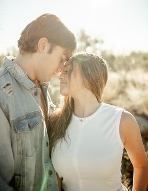 A gentle forehead touch between a couple wearing casual attire in golden hour lighting.