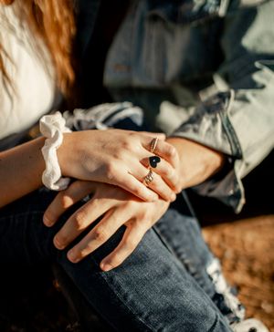 Close-up of hands wearing a scrunchie and ring against denim clothing.
