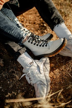 Two pairs of matching white combat boots on dusty desert ground.