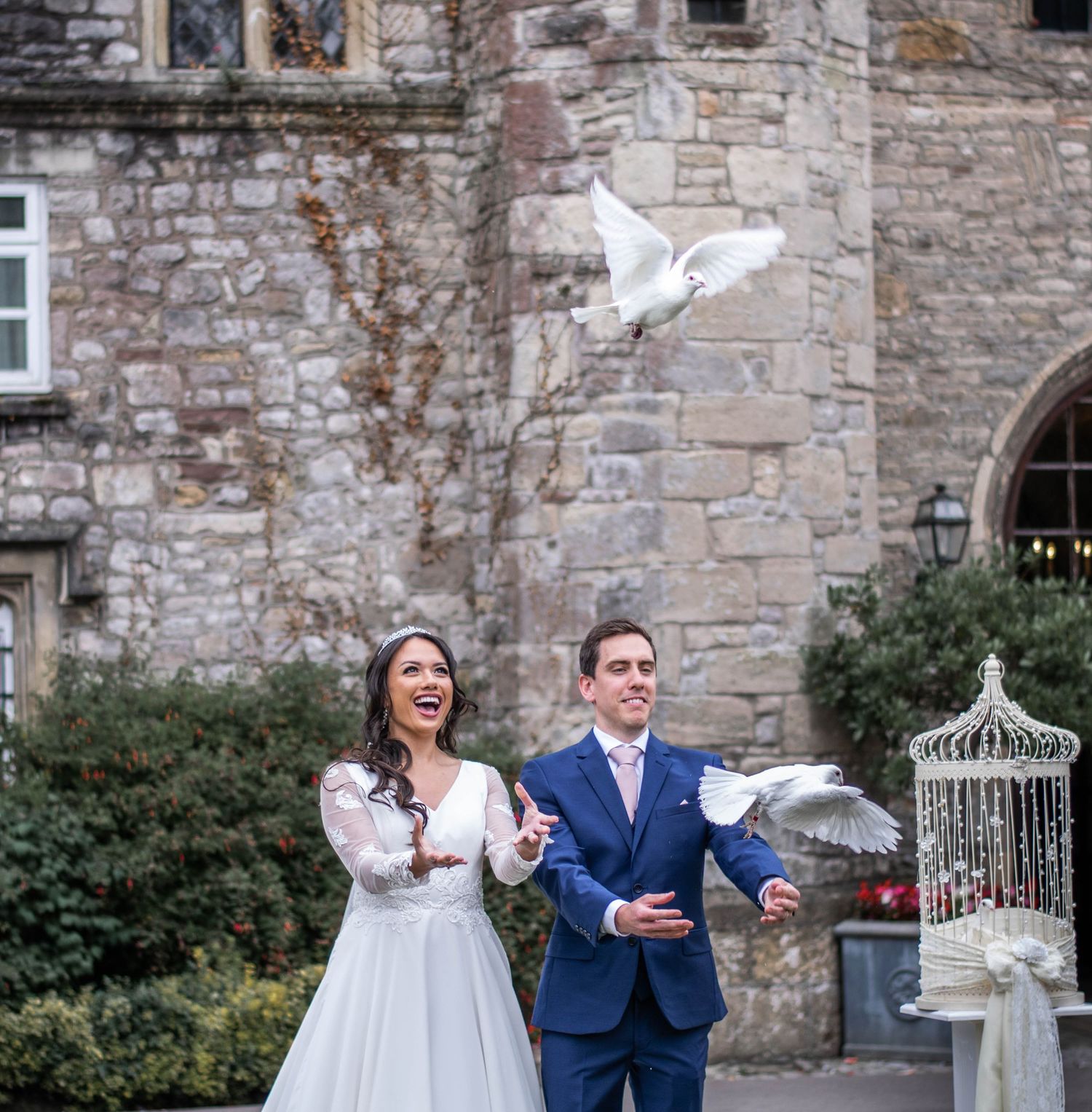 Joyful wedding celebration captured against rustic stone building backdrop.