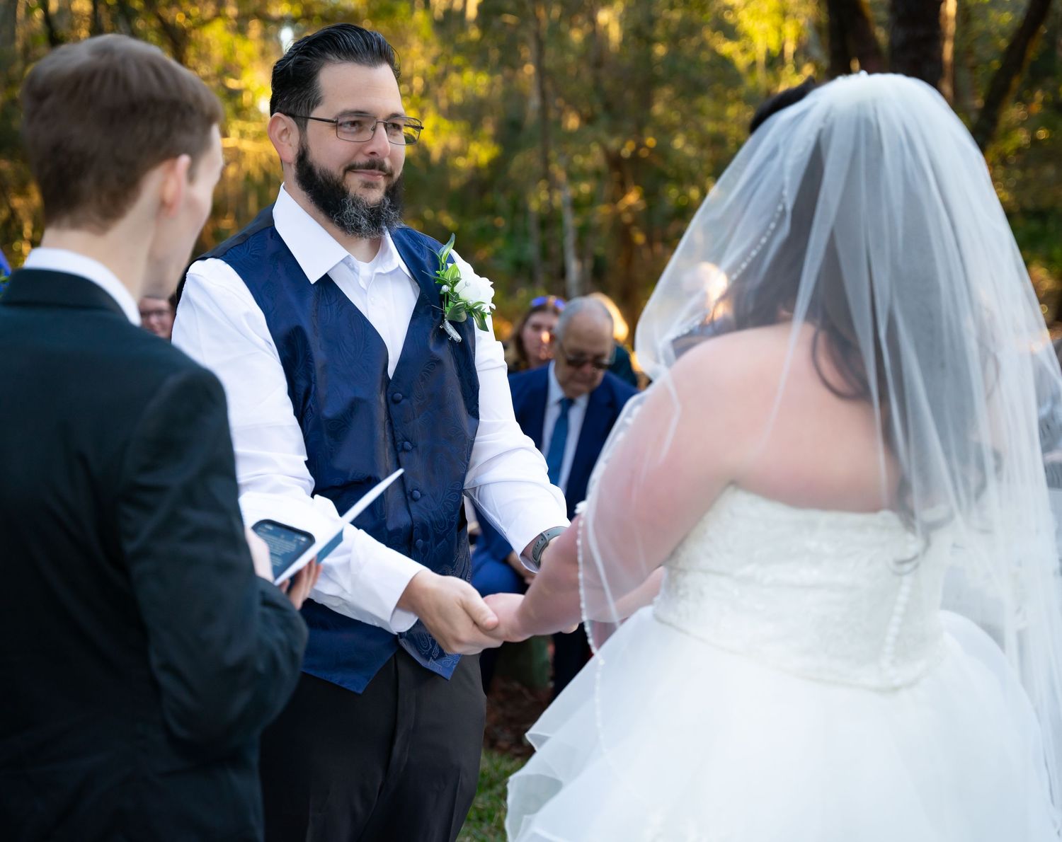 Wedding ceremony in progress under natural canopy of Spanish moss and oak trees.
