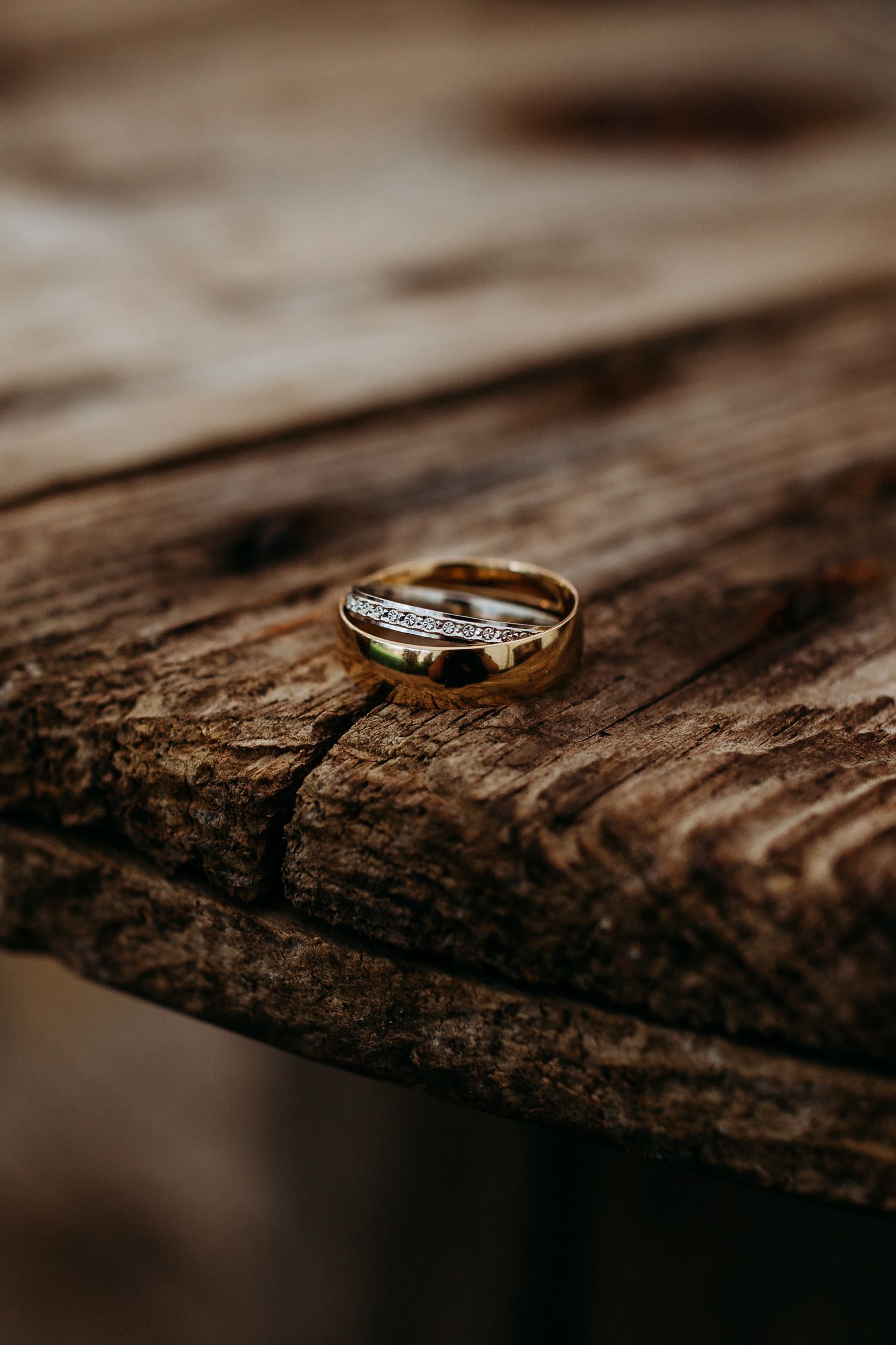 A detailed macro shot of a diamond wedding ring on weathered wood.