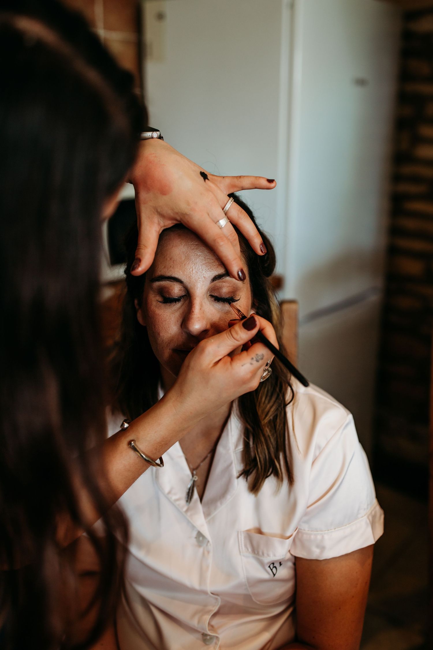 A close-up beauty shot showing makeup application during wedding preparations.