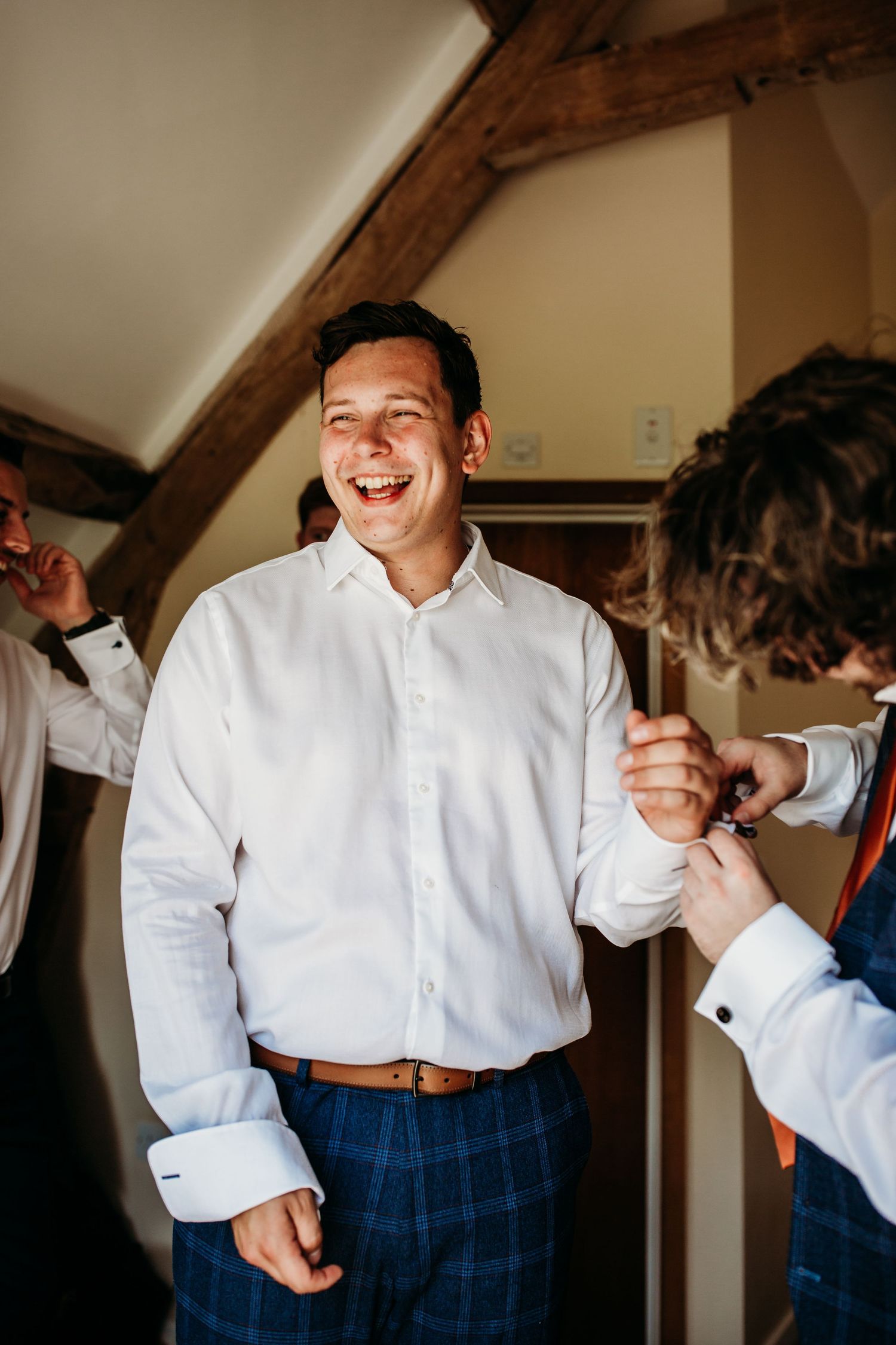 Person in formal white shirt and plaid pants getting ready indoors.