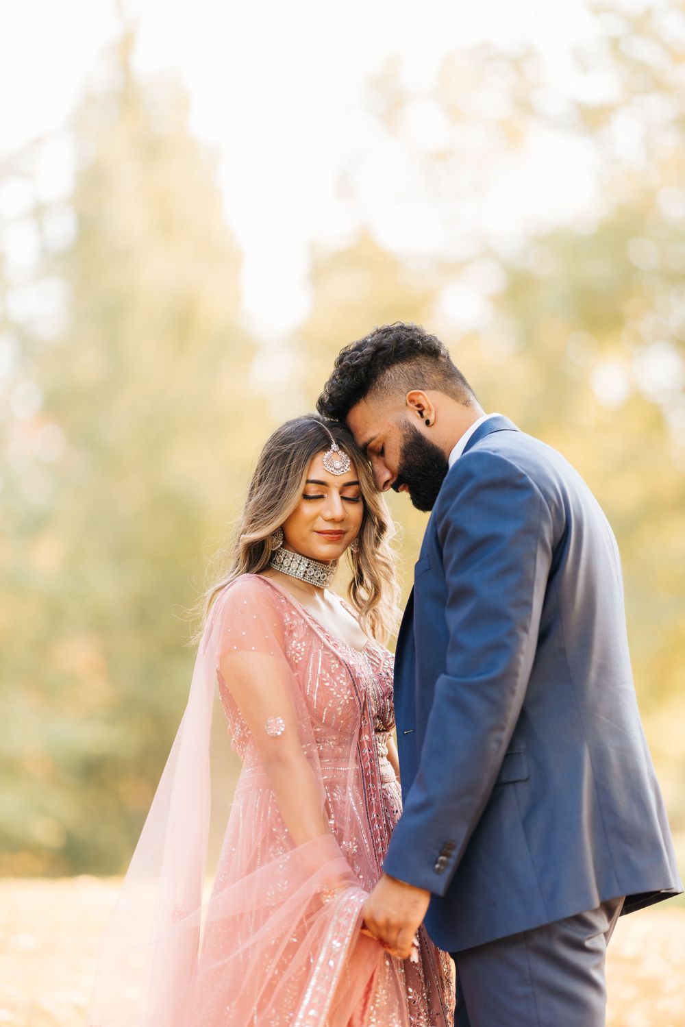 Intimate moment between couple in formal attire with soft golden lighting.