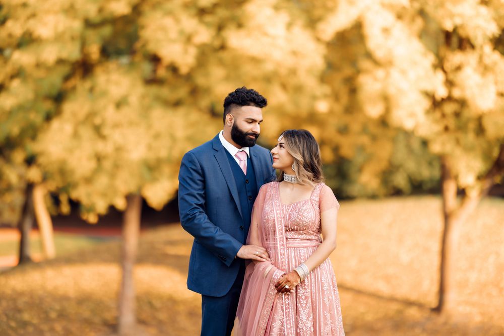 Romantic couple in formal wear standing together in a park with golden autumn trees.