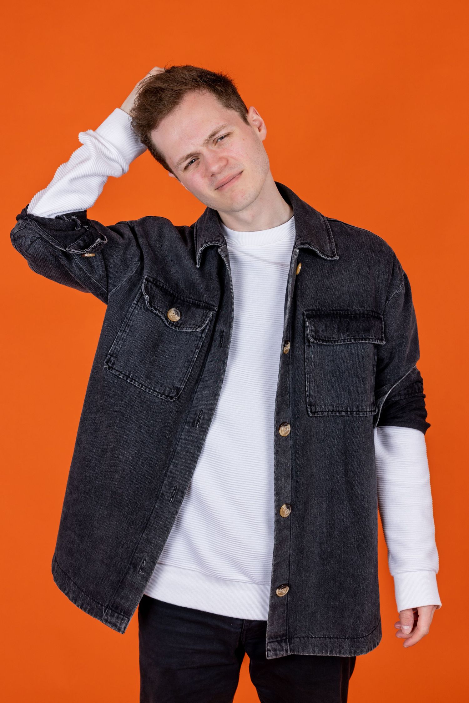 Comedian Oli Court shot in Amy Davies photography in Hove against a bright orange background.