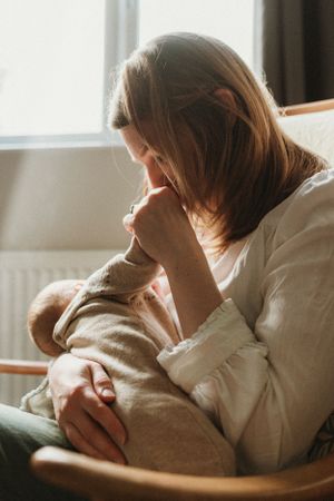 Tender moment between parent and baby in soft natural window light.