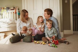 A casual family moment captured on the floor with toys and natural lighting.