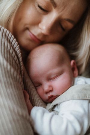 Intimate close-up of parent and sleeping newborn in soft, warm tones.